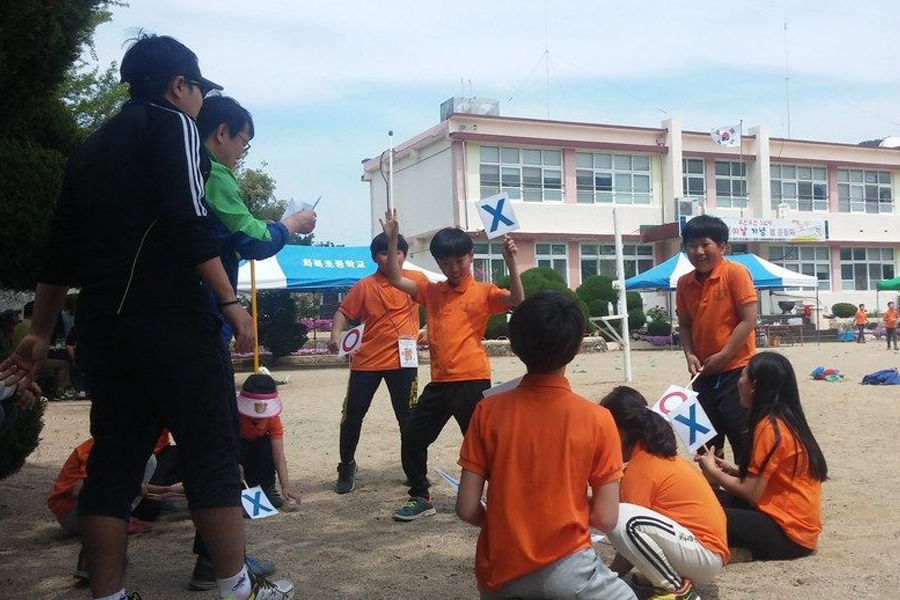 Children participating in a school activity, addressing the high educational expenses in South Korea.