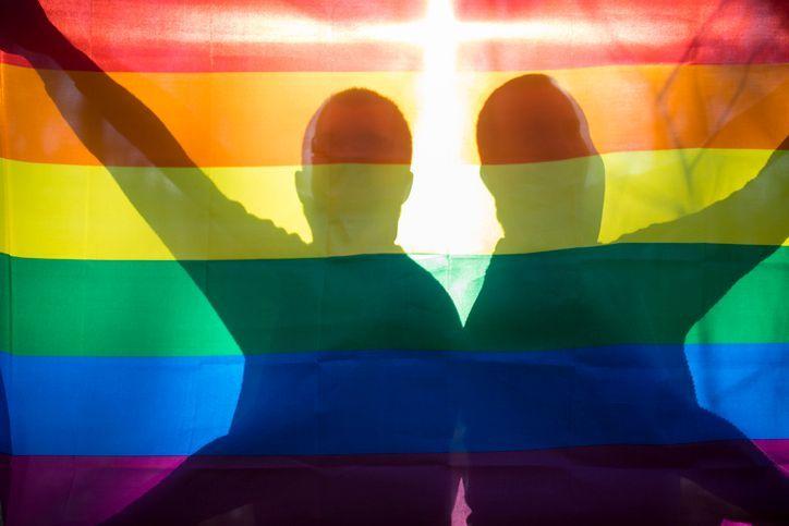 兩個人的剪影在彩虹旗後面，象徵著LGBTQ+的驕傲與平等。