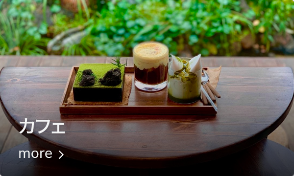 緑豊かな景色を背景に、おしゃれなカフェでのコーヒーとデザートが置かれたテーブルの写真