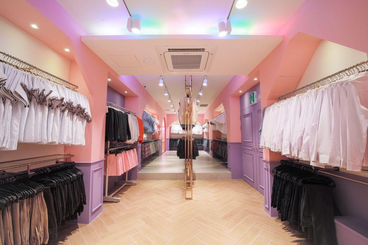 這是一間名為梨花校服店的內部照片，展示了這家店提供的各式校服，整齊地掛在衣架上。