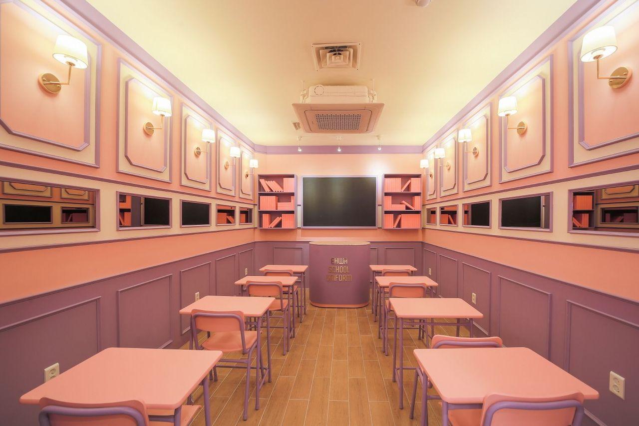 Photo of a visitor in a pink and grey school uniform at Ehwa School Uniform, showcasing popular outfit choices against brightly designed shop interior.