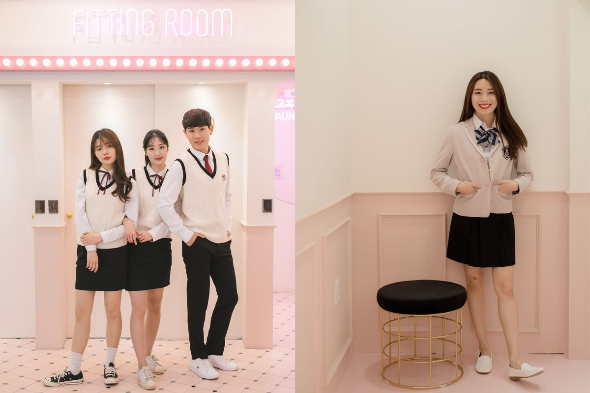 兩個人穿著韓國高中制服在梨花校服店的拍照區合影，背景為特殊設計的打卡牆。