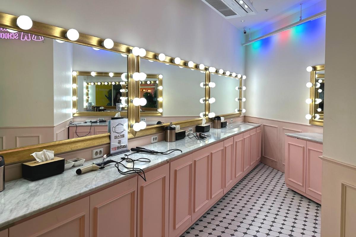 Elegant dressing room area at Ehwa School Uniform rental shop featuring luxurious lighting and ample vanity space for try-ons and touch-ups.