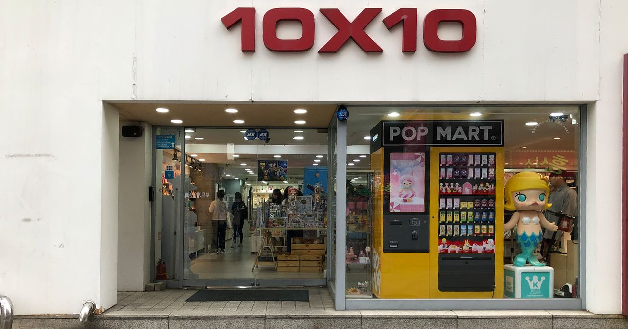 Entrance to 10x10 store in Seoul, featuring a vending machine and a colorful toy display, highlighting Korean retail culture.