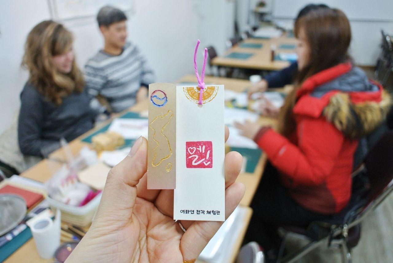 Instructors guiding a group through the seal engraving process at Insadong K-Art Center in Seoul, creating a hands-on cultural experience.