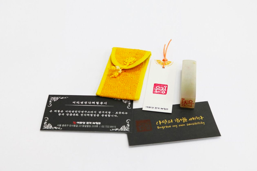 A handmade yellow pouch, personalized stamp, and instructional cards from Insadong K-Art Center.