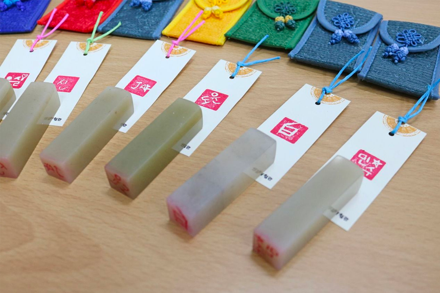Multiple personalized stone stamps with colorful tags at Insadong K-Art Center.
