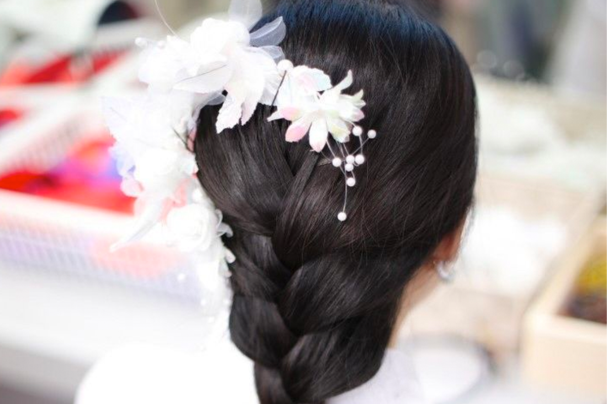 一名女子的辮子上佩戴著韓服的白色髮飾，展示韓服配件的優雅與華麗。」