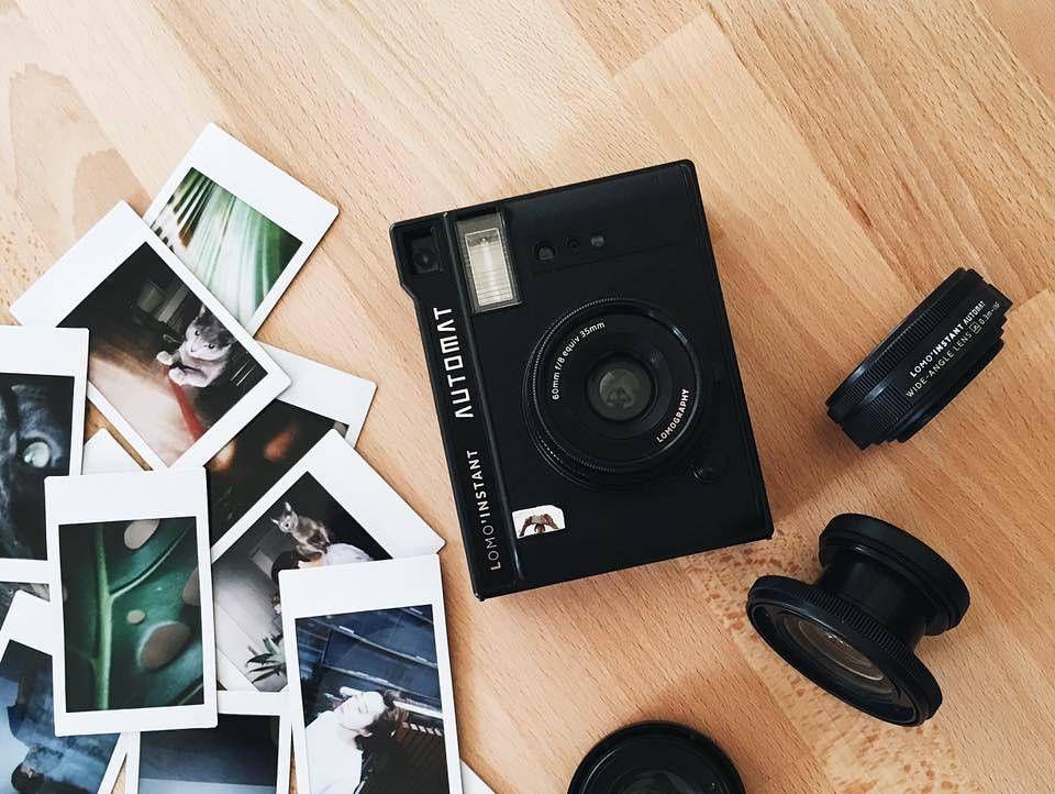 A vintage-style instant camera with a collection of vibrant instant photos around it.