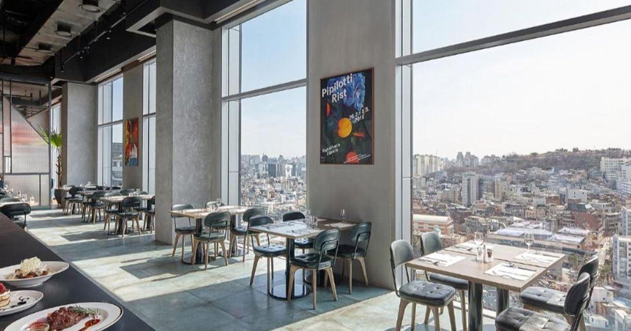 A contemporary restaurant offering panoramic city views from its large windows.