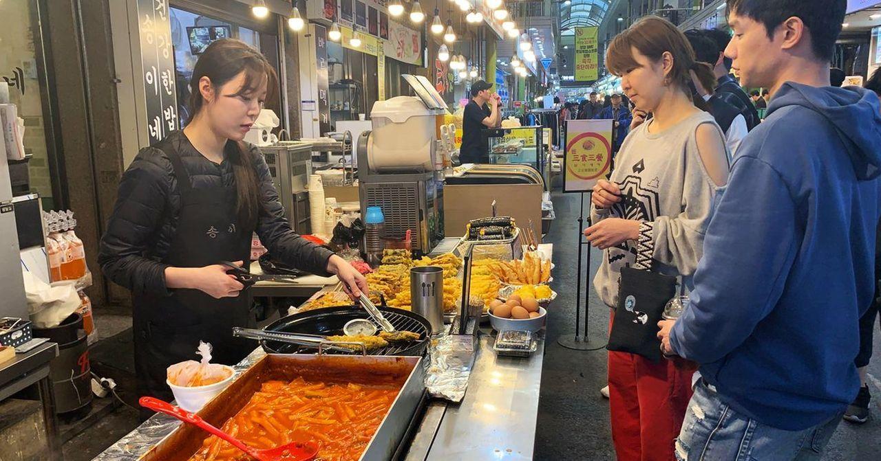 Street food vendor serving delicious Korean snacks at a lively market.