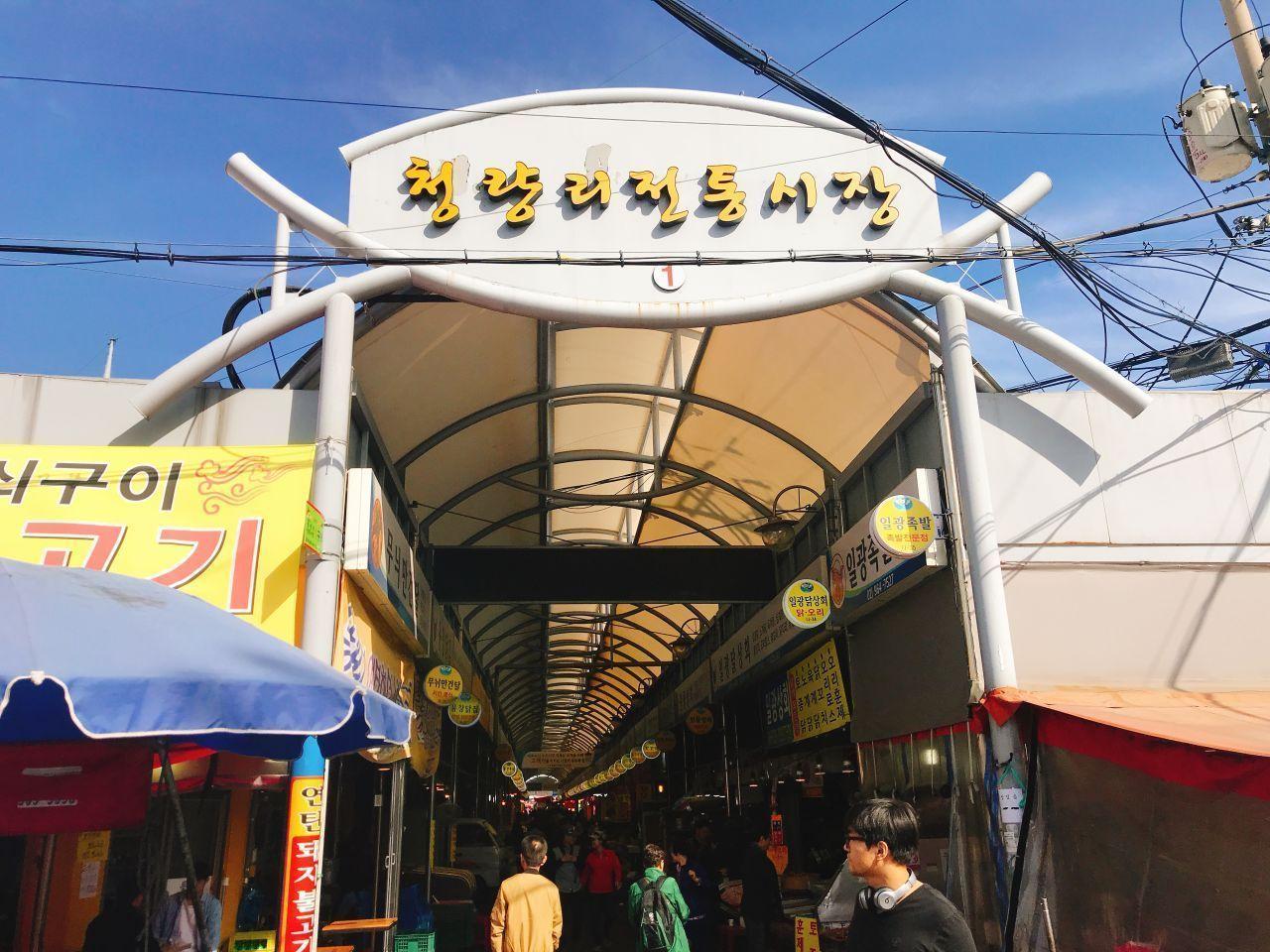 Entrance to a traditional market in Korea featuring vibrant signage and bustling activity.
