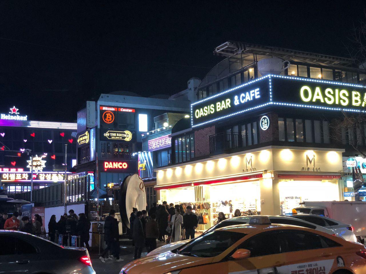 Bright and lively street view of a nightlife district in Korea filled with bars and cafes.