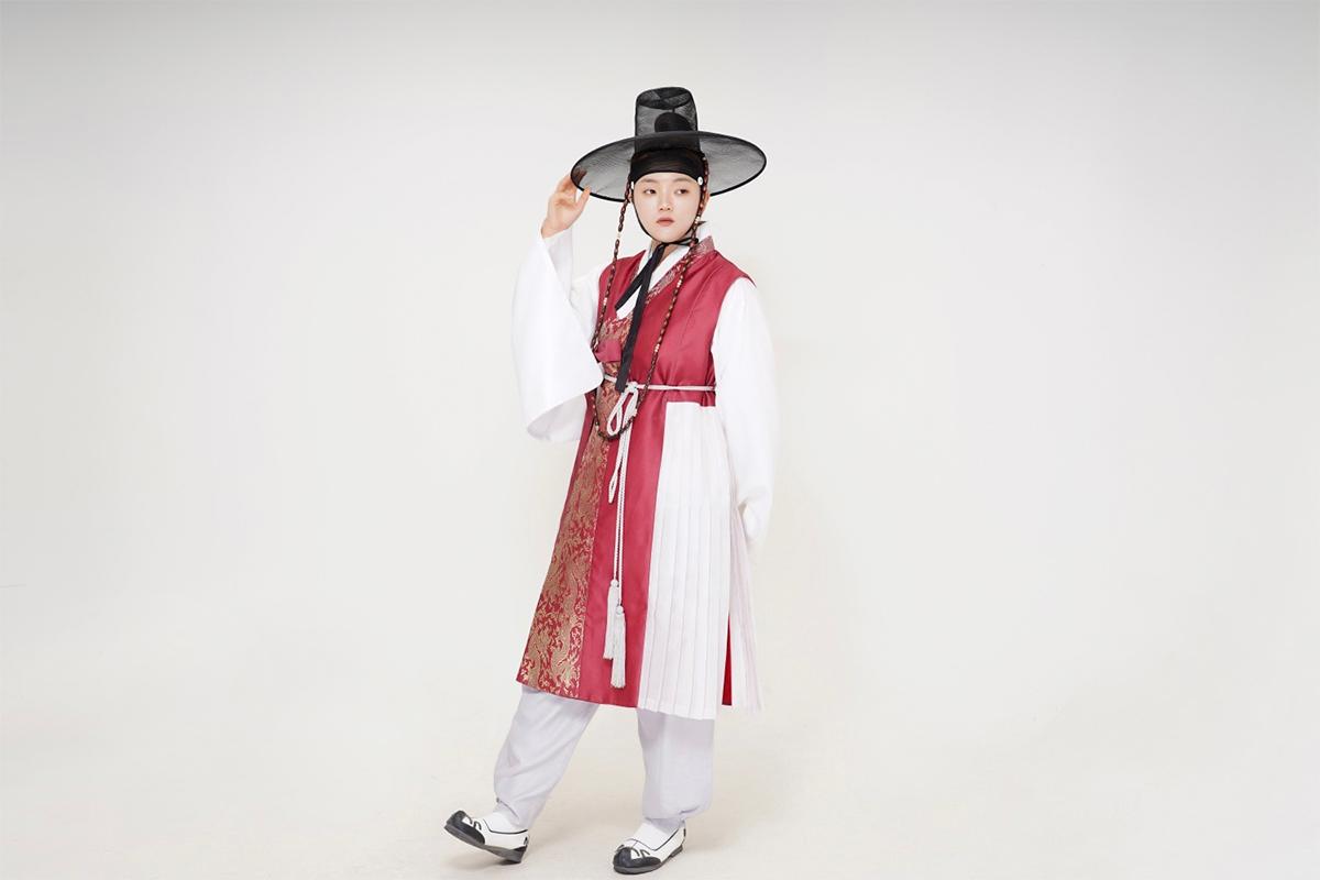 A man wearing a traditional Korean male hanbok with rich colors and patterns, complemented with a classic Korean hat.