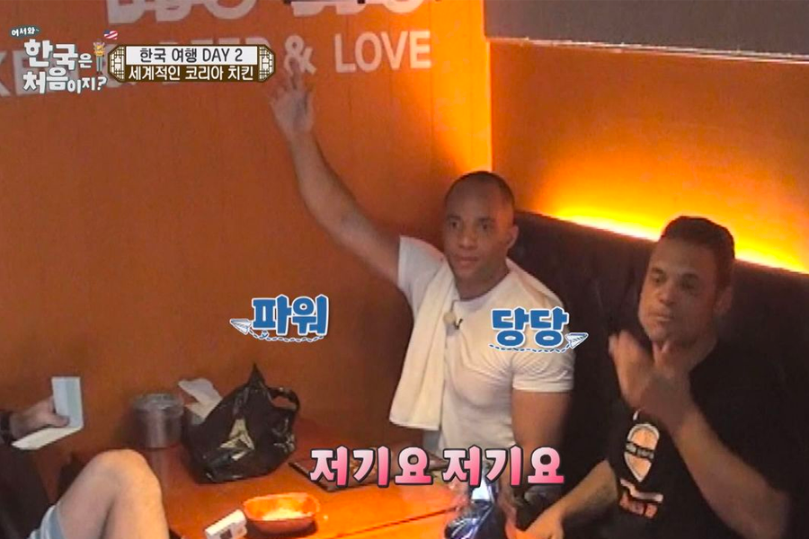 Person raising hand to call for service in a Korean restaurant, demonstrating how to get staff attention discreetly.