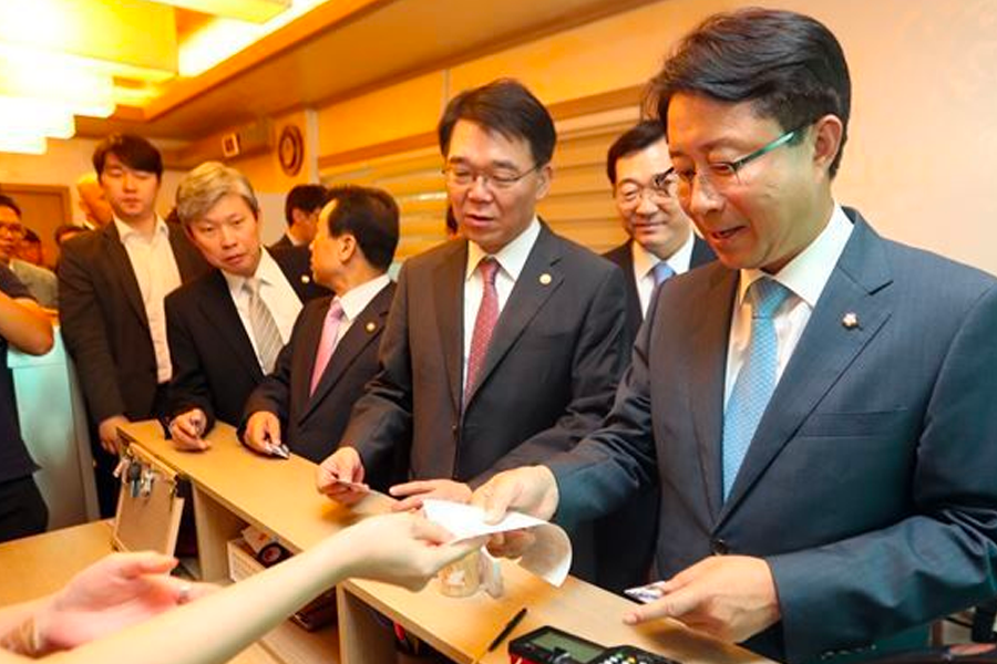 Cashier handling receipts and cards in a Korean restaurant, illustrating the process of paying in groups.