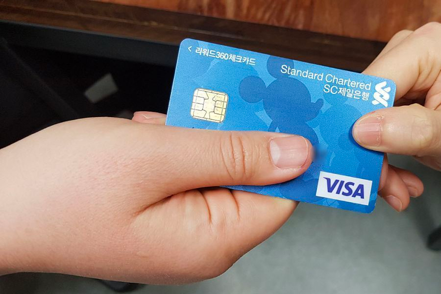 Close-up of a hand giving a credit card for payment in a Korean restaurant, emphasizing polite payment etiquette.