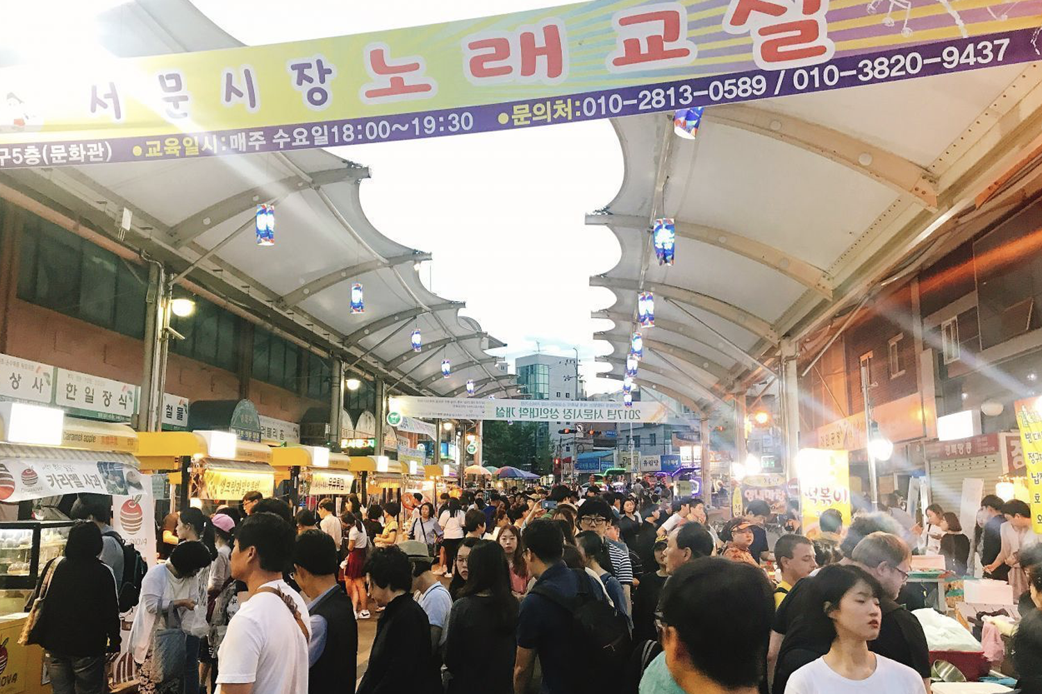 夜市人潮擁擠，市集內擺滿燈光裝飾的攤位，充滿熱鬧氣氛。