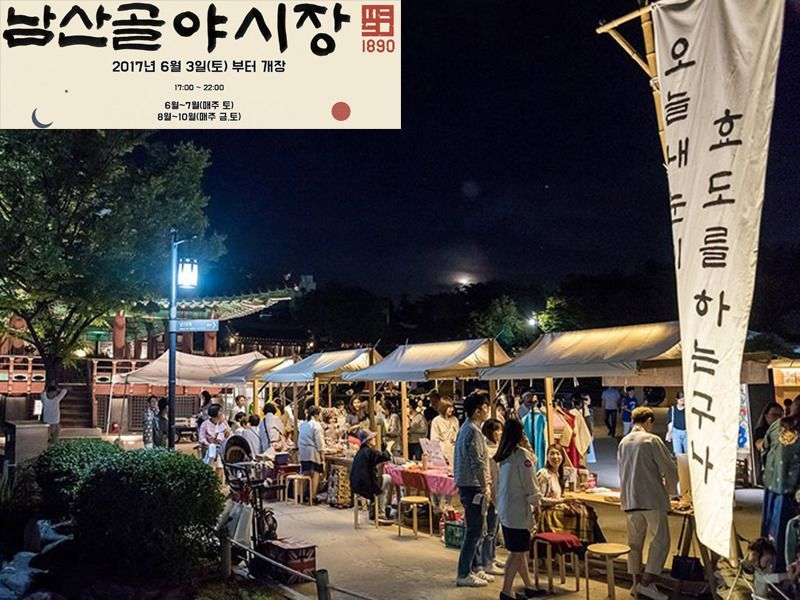 Outdoor night scene of Namsan Traditional Market in South Korea, with vendors and market goers illuminated by soft lighting.