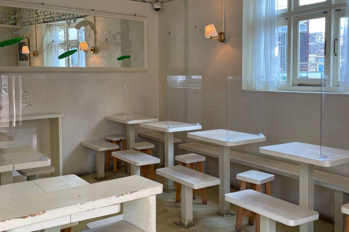 Cafe Layered's interior dining area in Yeonnam-dong, showcasing minimalist white furniture and ambient lighting.