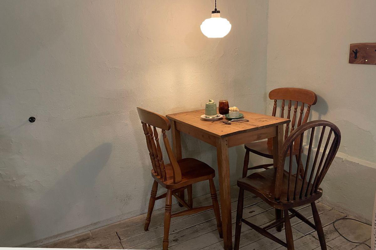 Interior seating at 'earth us' cafe in Yeonnam-dong, featuring a rustic wooden table and chairs with soft lighting.