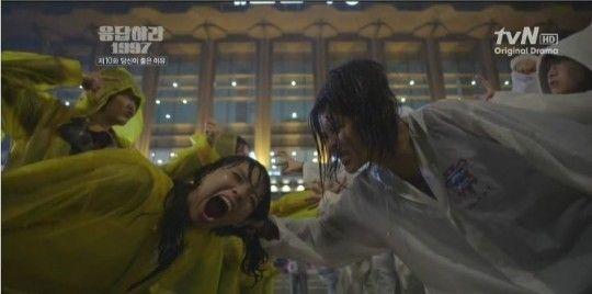 Scene from a drama depicting passionate K-pop fans in raincoats, showcasing the intense fan culture surrounding Korean idols.