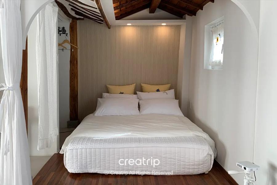 全州韩屋住宿中的一道内部视图，白色的床上用品搭配精致的木制结构，给人宁静温馨的感觉。