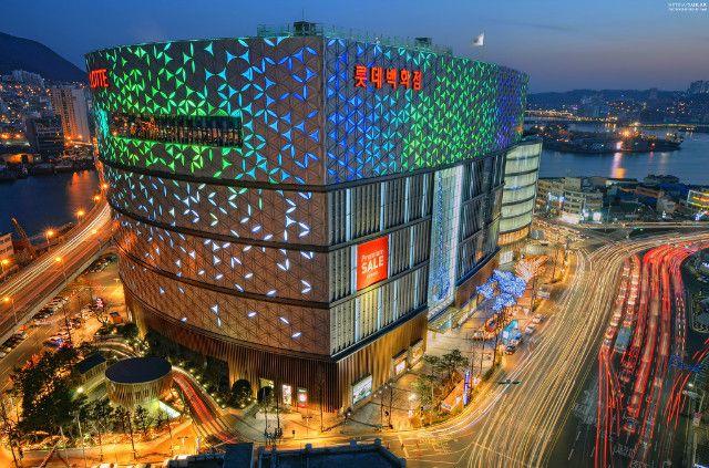 釜山南浦洞樂天百貨商場夜間外觀，展現其現代化設計和燈光效果。「樂天百貨位於南浦洞，是釜山地區購物和娛樂的熱門地點。」