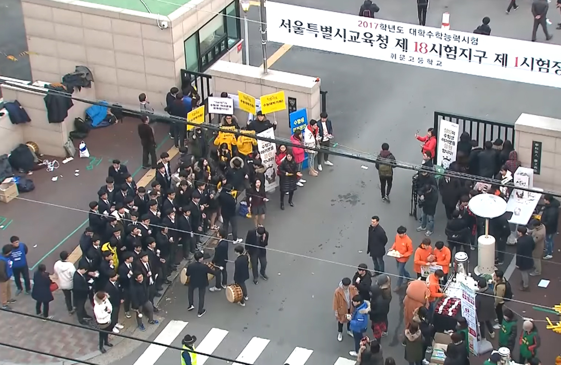 在韓國高考的校門口，學生們為修能考生們加油打氣，營造熱鬧氣氛。