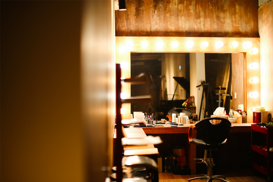 Time On Me Studio's makeup area with a large illuminated mirror, cosmetics, and a makeup chair, ideal for preparing before a photoshoot.