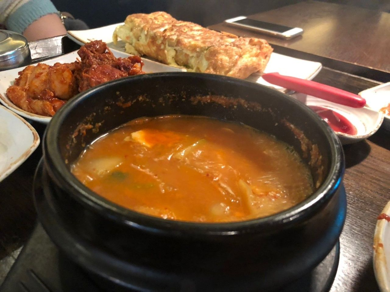 呈现出金色香味的大酱汤装在陶瓷碗中，旁边是配菜和米饭。