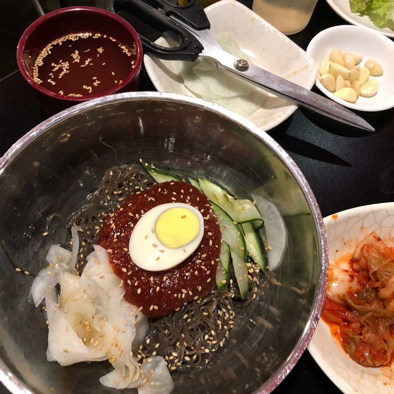 韩式辣拌冷面，拌上韩式辣椒酱，上面摆有黄瓜丝和半个煮鸡蛋。