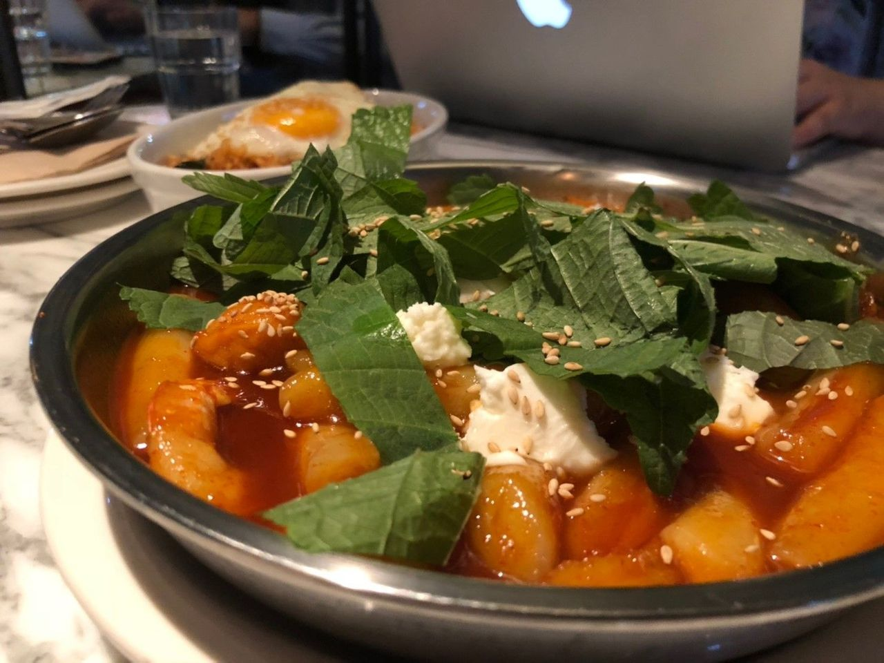 配有芝麻，鸡蛋和苏子的辣炒年糕，盛放在银色圆盘中。