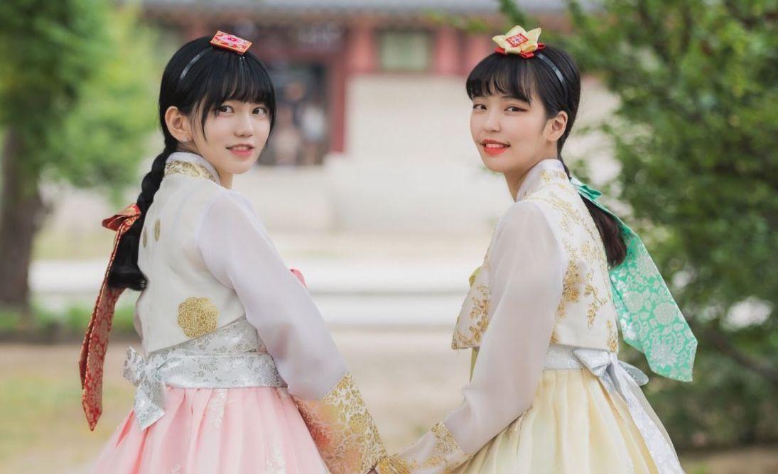 韓國首爾傳統韓服拍攝，兩位女性身穿華麗的韓服手牽手漫步在古宮殿內，展現出濃厚的傳統文化特色。