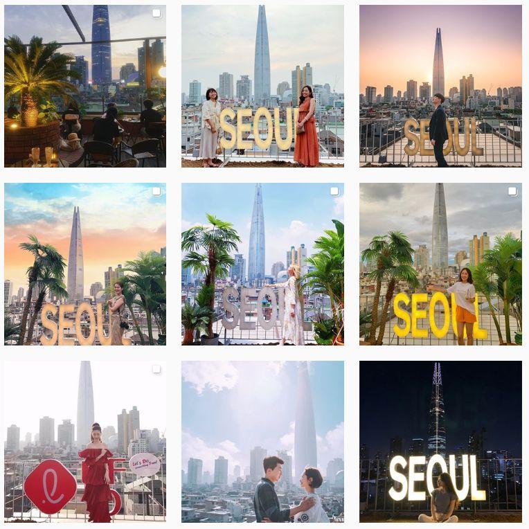 韓國Seoulism咖啡廳外景拍攝，顧客與樂天塔合影，標誌性的SEOUL字樣，展現首爾城市風景。