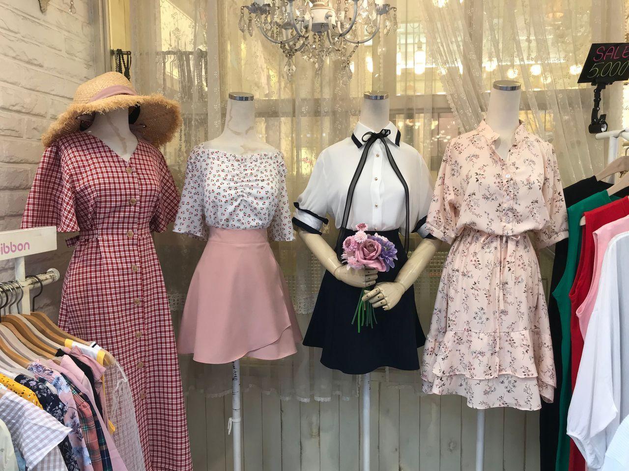 首爾某購物店櫥窗展示，春夏季節的清新連衣裙，粉紅色系，吸引女性顧客駐足。