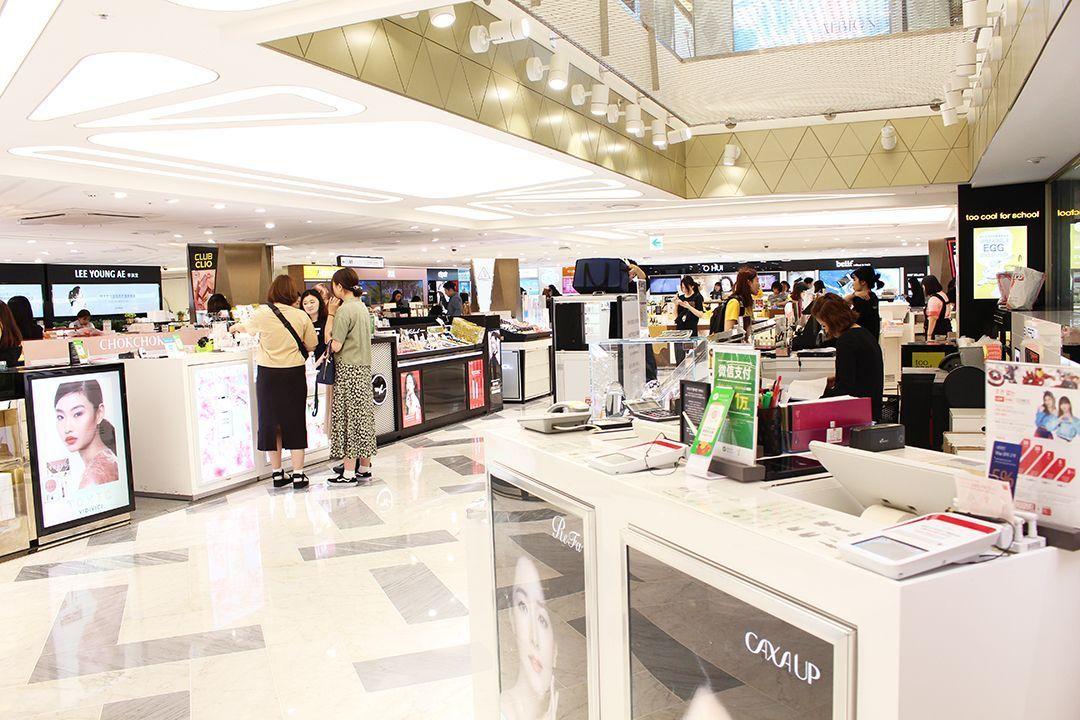 韓國免稅店購物景象，各大化妝品牌的專櫃在開放式的購物區域迎接顧客，便捷購物體驗。