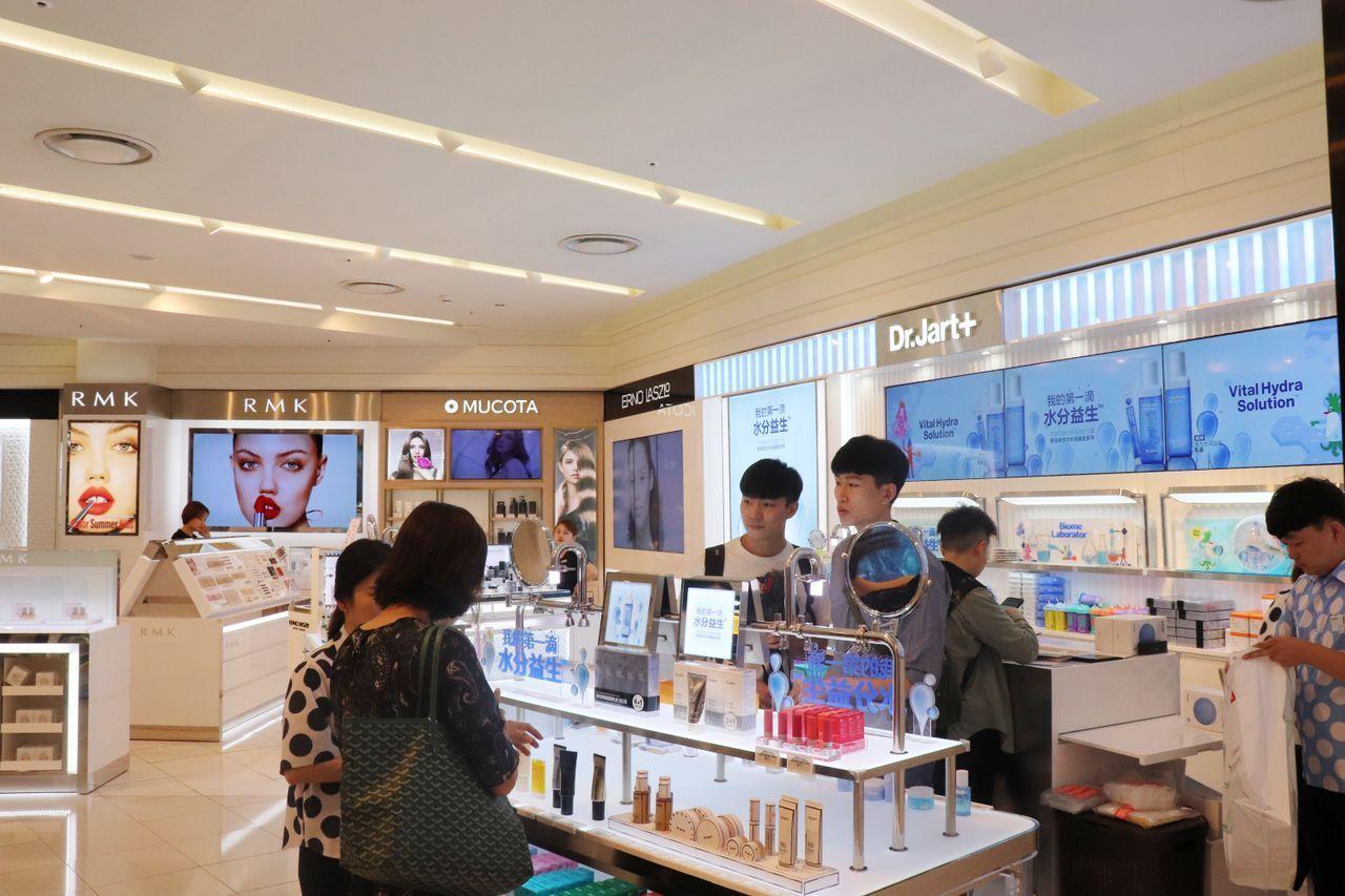 韓國樂天免稅店內的化妝品專櫃，顧客在四周環境明亮的商店裡參觀和挑選各色化妝品。