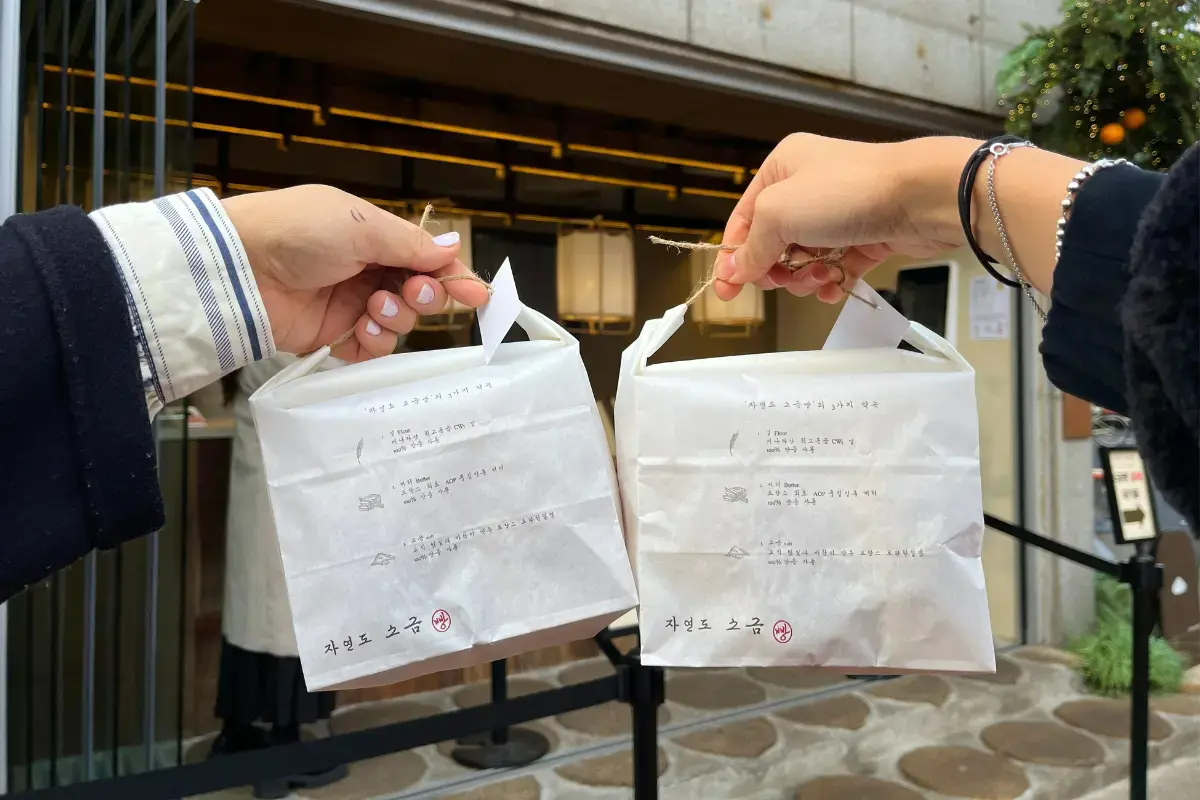 ジャヨンドソグムパンin聖水で購入した紙袋を持つ手。おしゃれなパッケージデザインが特徴的。