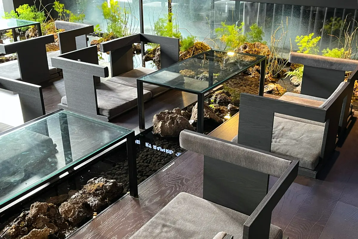 RAIN REPORT Croissantのカフェ内席。ガラスのテーブルとユニークな傢俱が並んでいる。