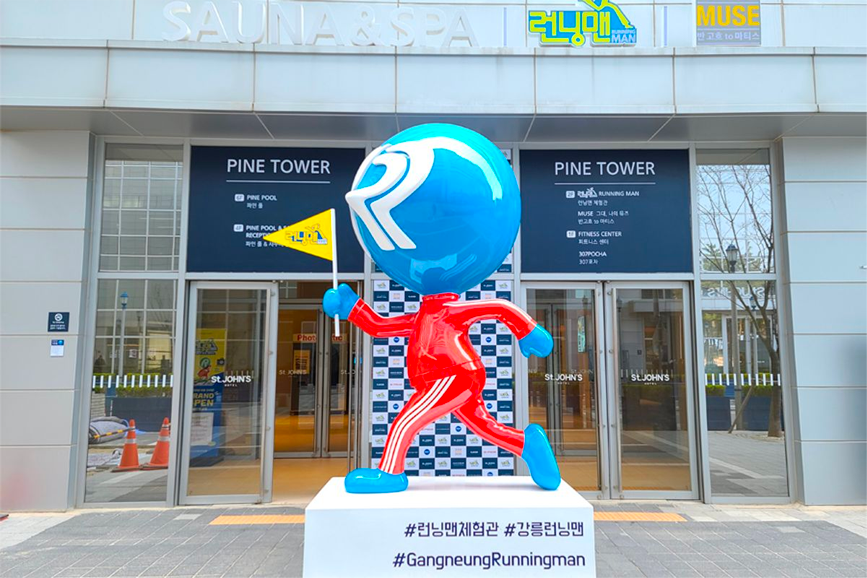 Entrance to Gangneung's Running Man Experience Center featuring the iconic Running Man character statue and logo at Pine Tower, inviting visitors to engage in fun activities based on a popular Korean variety show.