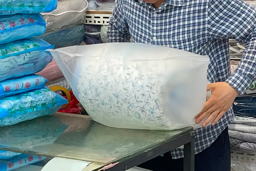 广藏市场棉被169号店提供的真空包装服务，工作人员正小心地为顾客打包棉被。