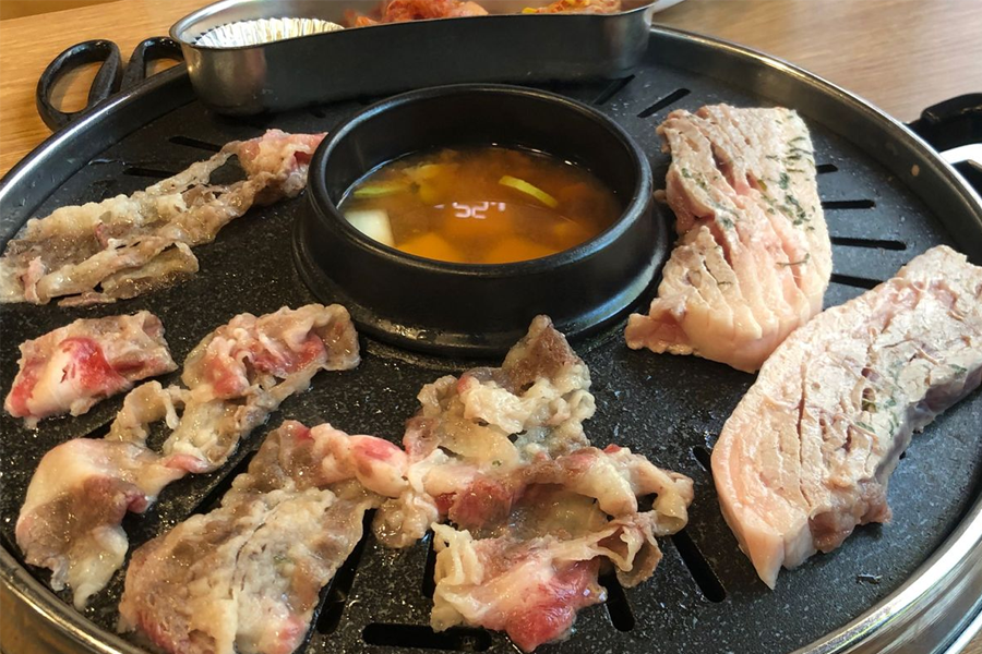 韓國弘大人氣任食燒肉店的桌上，正準備享用的燒肉、泡菜、配菜和佐料。