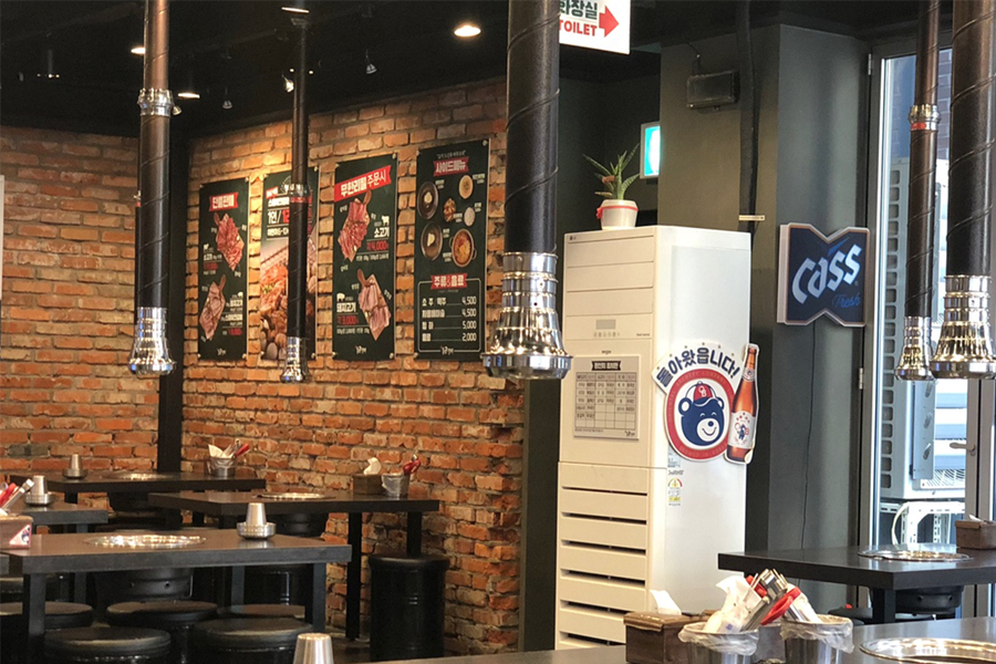 Interior of Tongkeun Galbi restaurant in Hongdae with brick walls, tables, and traditional BBQ exhaust hoods.