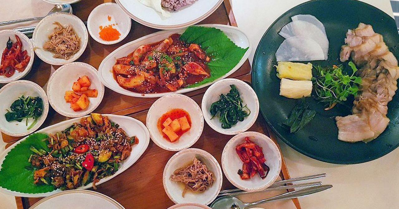 首尔江南地区丰富的韩式餐点，众多多样的小菜排一桌，是韩国美食文化的代表展示。