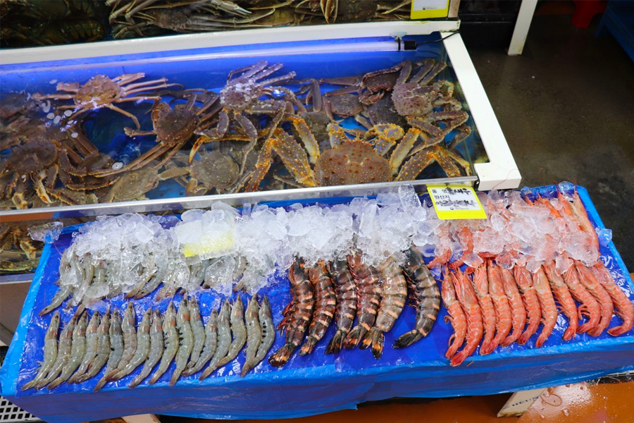 신선한 해산물이 시장에 진열되어 있는 모습. 다양한 해산물이 구매 가능한 활기찬 시장 풍경.