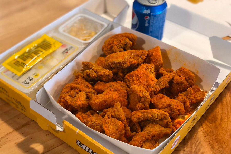 한국 스타일 프라이드 치킨이 상자에 담겨 있는 근접 사진, 노릇하게 튀겨진 닭고기가 입맛을 돋구는 매력적인 모습.