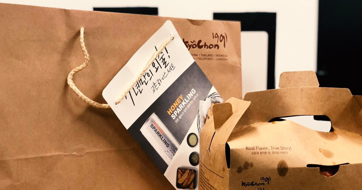 Túi giấy và hộp giao hàng của thương hiệu gà rán Kyochon Hàn Quốc với chân dung sản phẩm nổi bật.