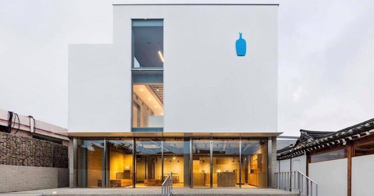 อาคารร้านกาแฟ Blue Bottle ในเกาหลีใต้ ภายนอกอาคารมีการออกแบบที่ดูทันสมัยและเรียบง่าย ด้านหน้าอาคารมีเครื่องหมายบลูบอเทิลสีฟ้าโดดเด่น