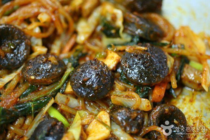 韓國小吃血腸的特寫，稻麥麵條和各色蔬菜伴著烤好的血腸片。